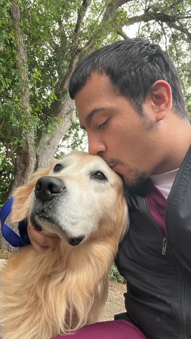 Xavier Centeno kissing a senior golden retriever on the head outdoors in Broward County